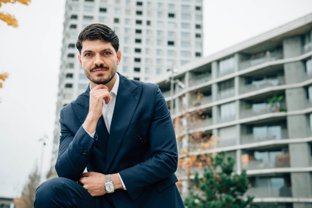 properti Immobilienmakler Luca Lauria vor modernen Mehrfamilienhäusern in Zürich.